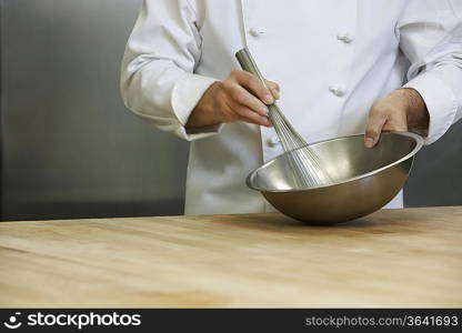 Male chef mixing ingredients using whisk, mid section