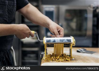 male chef using machine chop fresh pasta dough. High resolution photo. male chef using machine chop fresh pasta dough. High quality photo