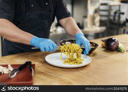 male chef with gloves putting pasta plate