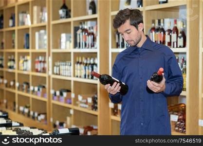 male choosing between two bottles of wine