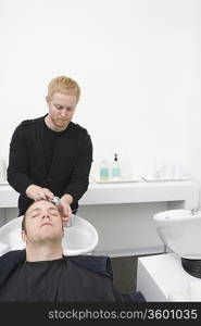 Male client has hair shampooed in unisex hair salon