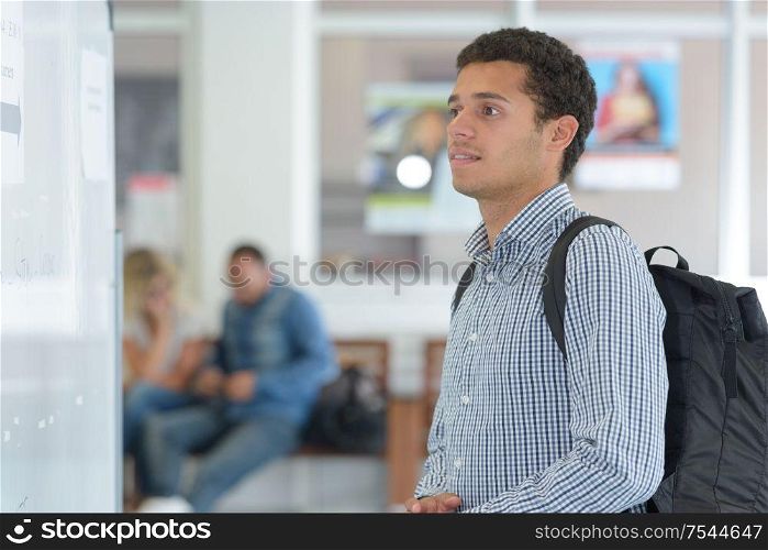 male college student looking at notice board