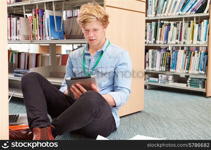 Male College Student Studying In Library With Digital Tablet