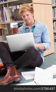 Male College Student Studying In Library With Laptop