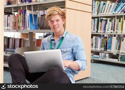 Male College Student Studying In Library With Laptop