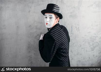Male comedy artist posing, pantomime with white makeup mask. Circus actor in suit, gloves and hat. Male comedy artist posing, circus actor