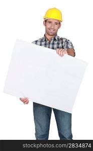 Male construction worker holding blank advertising board
