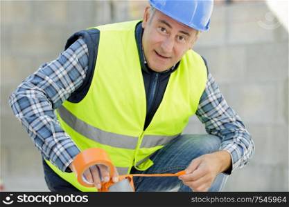 male construction worker in safety helmet near measuring pipes