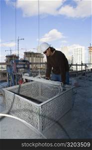 Male construction worker leaning against a basket at a construction site
