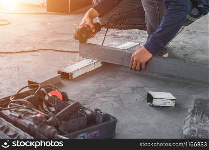 Male construction worker using electrical angle grinder for cutting iron bars with sharp fire sparks in construction site. Copy space wallpaper.