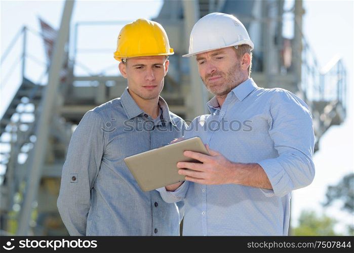 male construction workers discussing over digital tablet