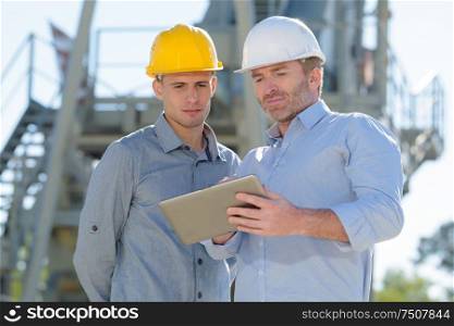 male construction workers discussing over digital tablet