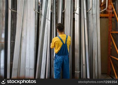 Male constructor choosing repair materials in hardware store. Builder in uniform look at the goods in diy shop