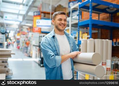 Male consumer buying wallpapers in hardware store. Customer look at the goods in diy shop, shopping in building supermarket