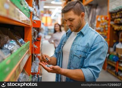 Male consumer choosing nuts in hardware store. Customer look at the goods in diy shop, shopping in building supermarket. Male consumer choosing nuts in hardware store