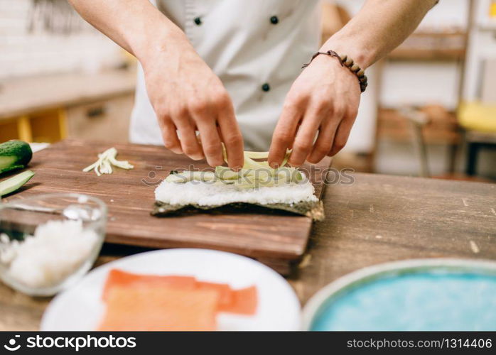 Male cook hands, making sushi rolls, seafood. Traditional japanese cuisine, preparation process. Male cook hands making sushi rolls, seafood