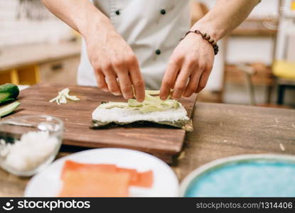 Male cook hands, making sushi rolls, seafood. Traditional japanese cuisine, preparation process. Male cook hands making sushi rolls, seafood