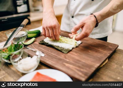 Male cook hands, making sushi rolls, seafood. Traditional japanese cuisine, preparation process. Male cook hands making sushi rolls, seafood