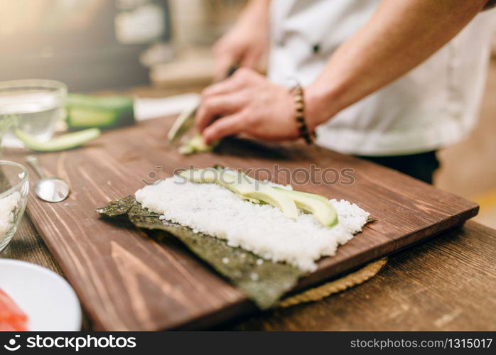 Male cook hands, making sushi rolls, seafood. Traditional japanese cuisine, preparation process. Male cook hands making sushi rolls, seafood