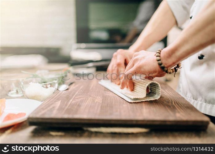 Male cook making seafood on wooden table, asian food preparation process. Traditional japanese cuisine, sushi ingredients