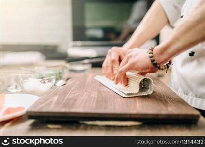 Male cook making seafood on wooden table, asian food preparation process. Traditional japanese cuisine, sushi ingredients