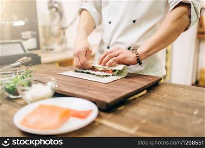 Male cook making seafood on wooden table, asian kitchen preparation process. Traditional japanese cuisine, sushi ingredients. Male cook making seafood, asian kitchen