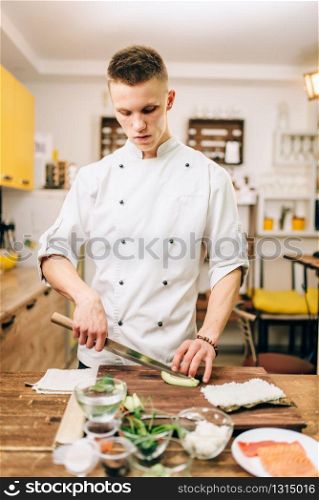 Male cook making sushi rolls on the kitchen. Traditional japanese food, preparation process, seafood