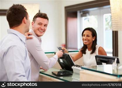 Male Couple Checking In At Hotel Reception