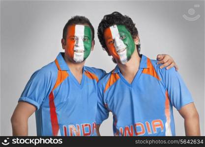 Male cricket fans with face painted in tricolor standing together over colored background