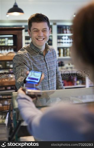 Male Customer Making Contactless Payment For Shopping Using Mobile Phone In Delicatessen