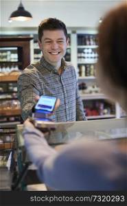 Male Customer Making Contactless Payment For Shopping Using Mobile Phone In Delicatessen