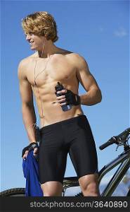 Male cyclist holding water bottle, outdoors