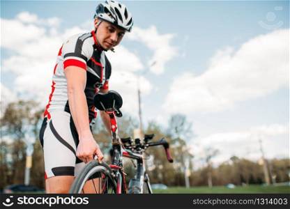 Male cyclist in helmet and sportswear prepares before bike competition. Workout on bike path, bycycle race