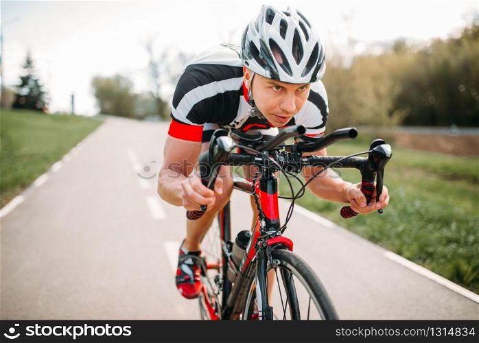 Male cyclist in helmet and sportswear rides on bicycle, front view. Workout on bike path, cycling. Male cyclist rides on bicycle, front view