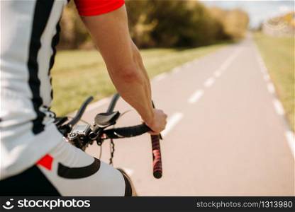 Male cyclist in sportswear, cycling on asphalt road. Male sportsman rides on bicycle. Workout on bike path. Male cyclist in sportswear cycling on asphalt road