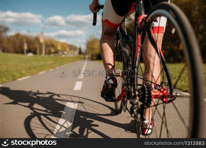 Male cyclist on bike path, view from the rear wheel. Cycling on asphalt road. Sportsman rides on bicycle, bycyclist on workout. Cyclist on bike path, view from the rear wheel