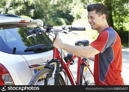 Male Cyclist Taking Mountain Bike From Rack On Car