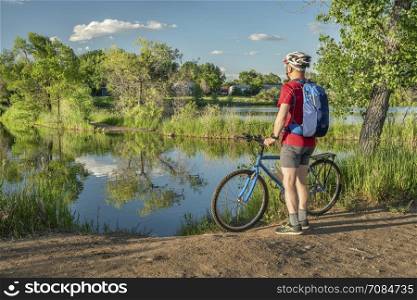 male cyclist with a mountain bike on a lake shore, summer scenery in Colorado