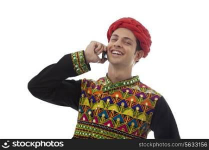 Male dandiya dancer talking on a mobile phone