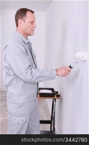 Male decorating painting a room white