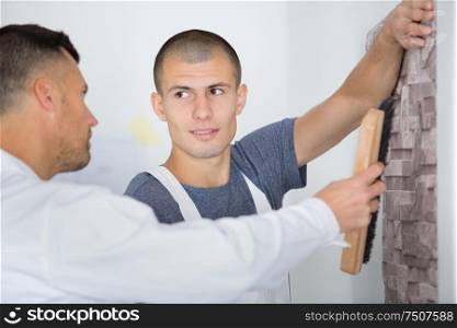 male decorator painting wall with brush indoors