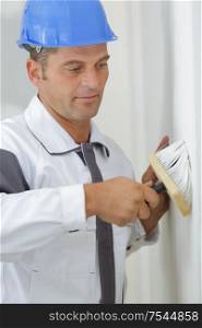 male decorator using large brush on wall