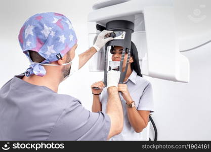 Male dentist adjusting a tooth whitening machine used by a female patient in a dental clinic. Dentist adjusting a tooth whitening machine used by a patient in a dental clinic