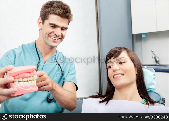 Male dentist explaining a female patient denture work in dental clinic. Dentist explains a female patient denture work in clinic