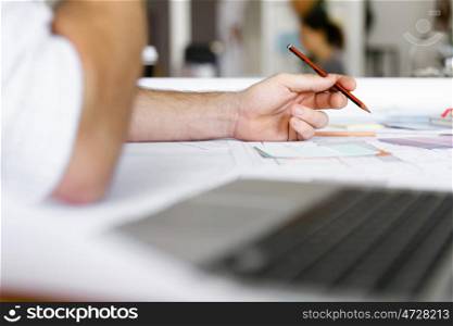 male designer working at desk. Male architect with computer studying plans in office