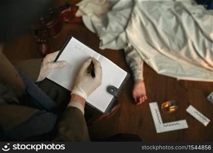 Male detective with cigar writes in notebook, victim under the cape at the crime scene, retro style. Criminal investigation, inspector is working on a murder, vintage room interior on background. Male detective with cigar writes in notebook