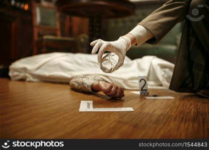 Male detective with magnifying glass looking evidence at the crime scene, retro style. Criminal investigation, inspector is working on a murder, vintage room interior on background. Detective with magnifying glass looking evidence