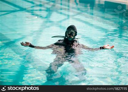 Male diver in scuba gear poses in pool, course in diving school. Teaching people to swim underwater, indoor swimming. Man with aqualang. Male diver in scuba gear poses in pool, diving