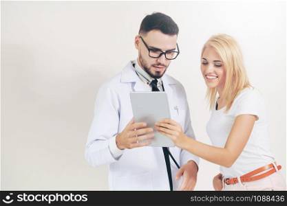 Male doctor and female patient looks at tablet computer for health data record. Healthcare and medical service.