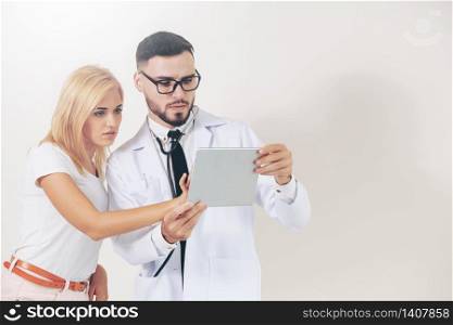 Male doctor and female patient looks at tablet computer for health data record. Healthcare and medical service.. Male Doctor and Female Patient in Hospital.